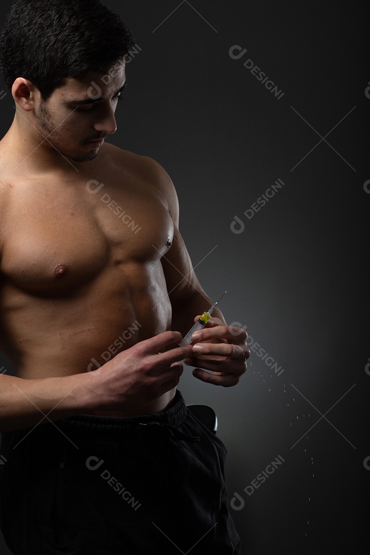 Homem musculoso com uma seringa na mão. Usuário de esteroides anabolizantes para treinamento de força