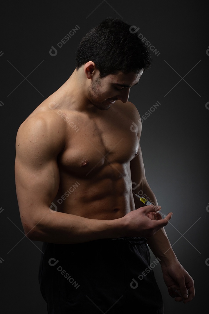 Homem musculoso com uma seringa na mão. Usuário de esteroides anabolizantes para treinamento de força
