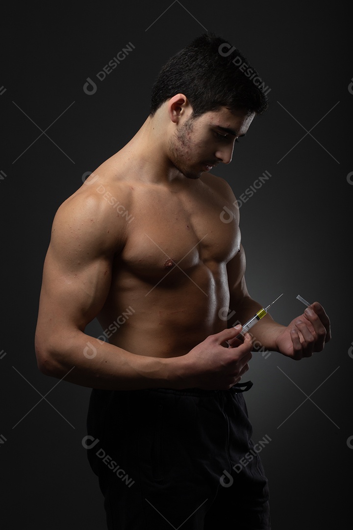 Homem musculoso com uma seringa na mão. Usuário de esteroides anabolizantes para treinamento de força