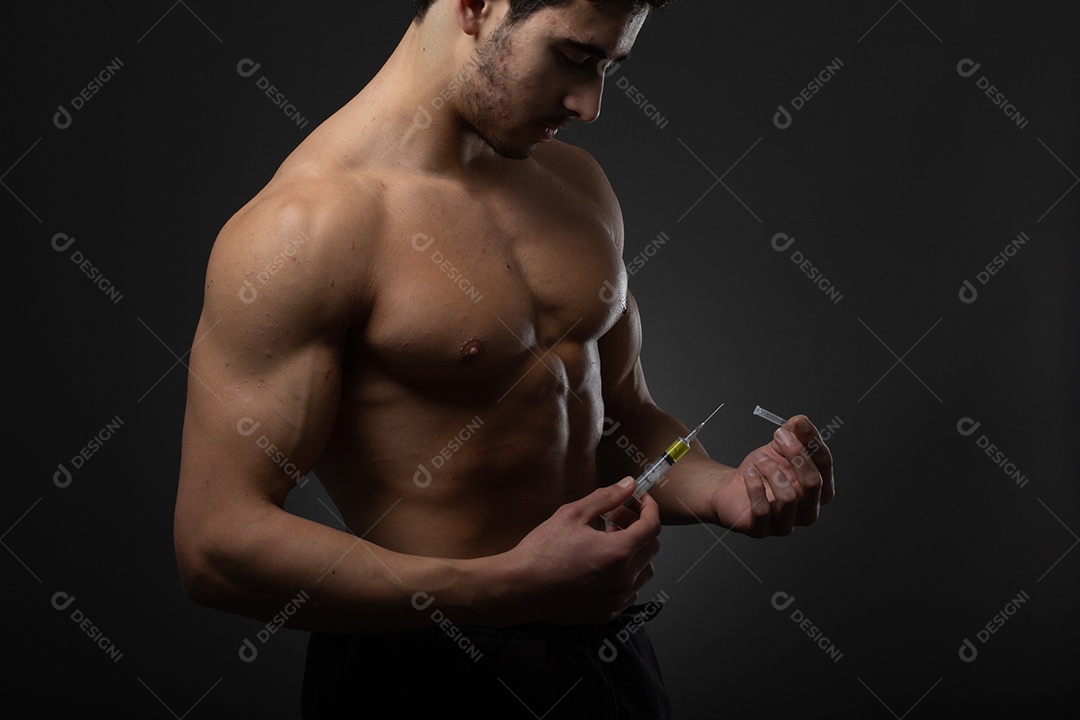 Homem musculoso com uma seringa na mão. Usuário de esteroides anabolizantes para treinamento de força