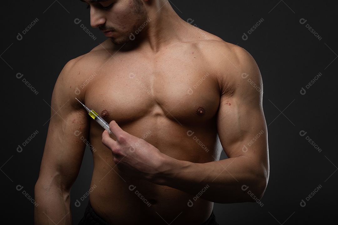 Homem musculoso com uma seringa na mão. Usuário de esteroides anabolizantes para treinamento de força