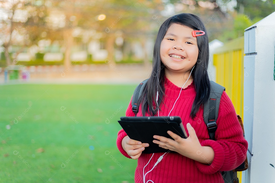 Menina asiática observando uma mesa no gramado da escola