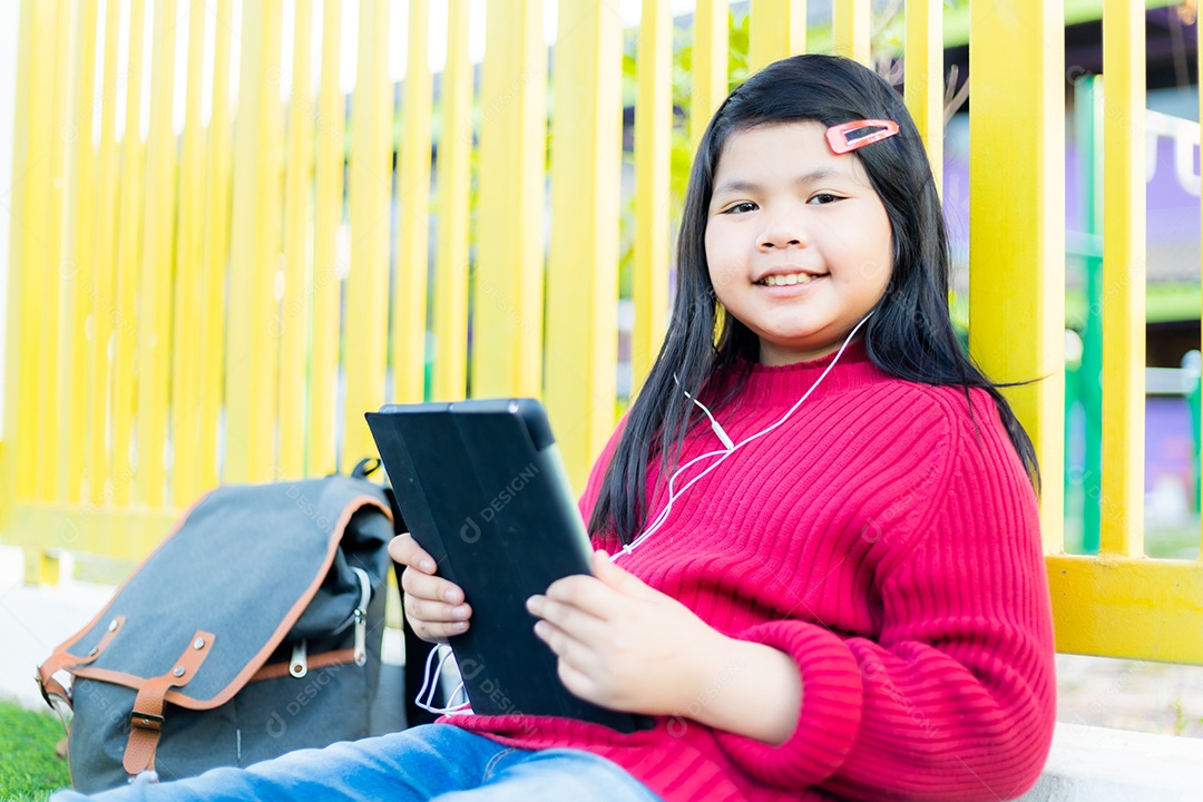 Menina asiática observando uma mesa no gramado da escola