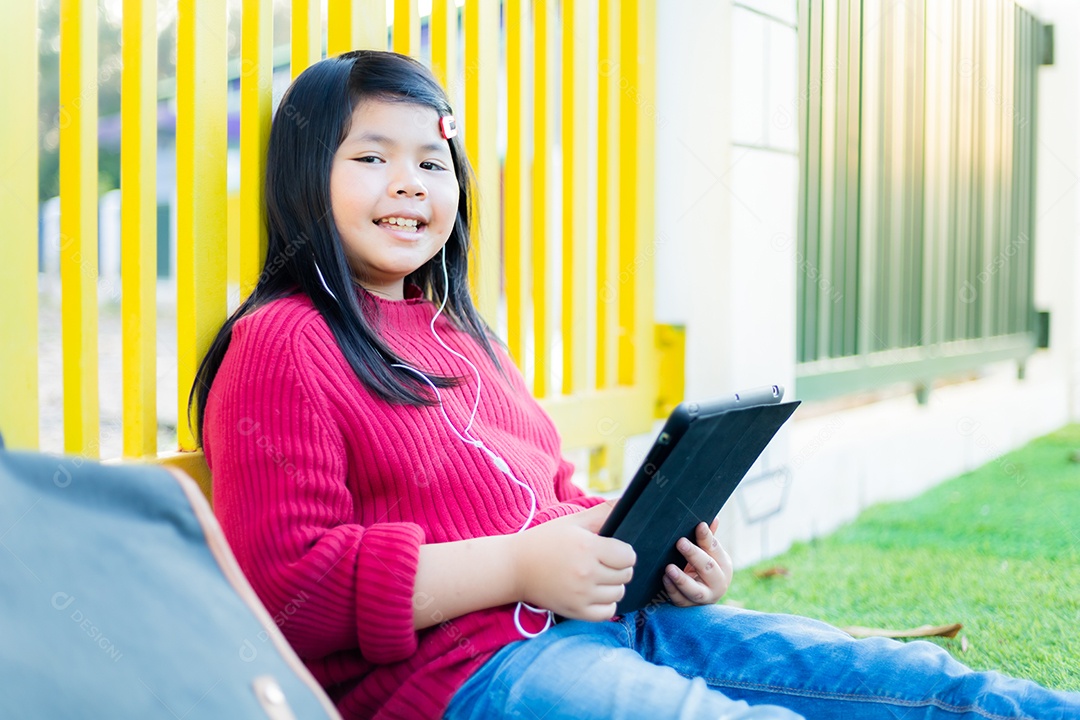 Menina asiática observando uma mesa no gramado da escola