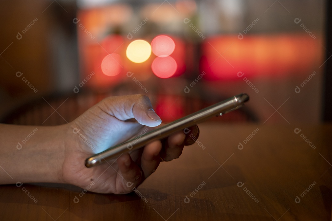 smartphone na mão, jogando o smartphone na cafeteria, mostre o bokeh atrás da luz da vela, pegue Phon, Khonkean, Tailândia, 19 mach 2021