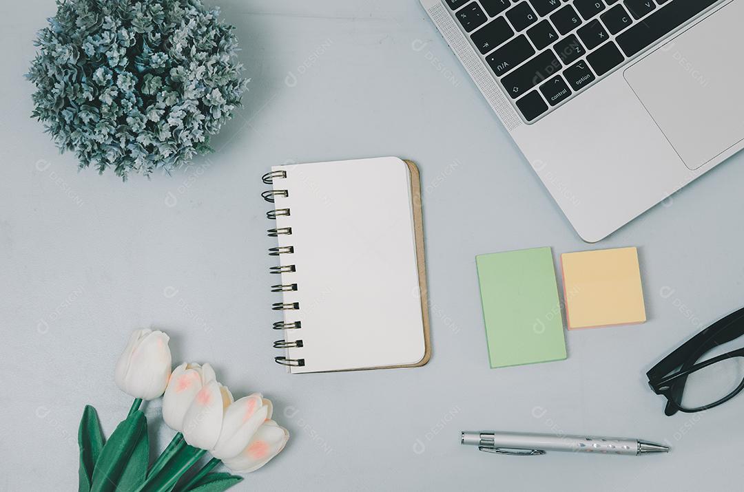 Vista superior computador portátil flor de bloco de notas em branco e caneta na mesa. postura plana com espaço de cópia do escritório de mesa.