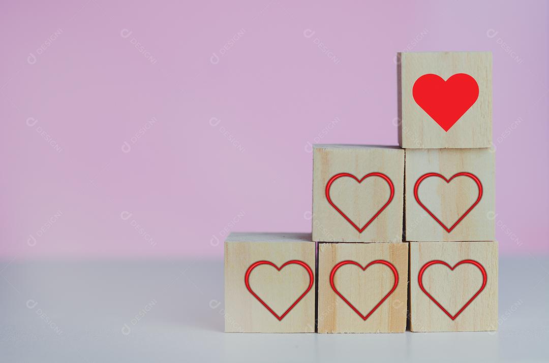 Cubos de madeira com coração símbolo de amor vermelho no fundo rosa