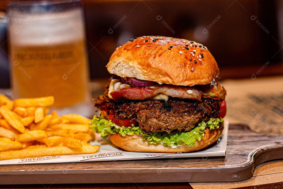 Hambúrguer com batata frita servidos em tabua de madeira
