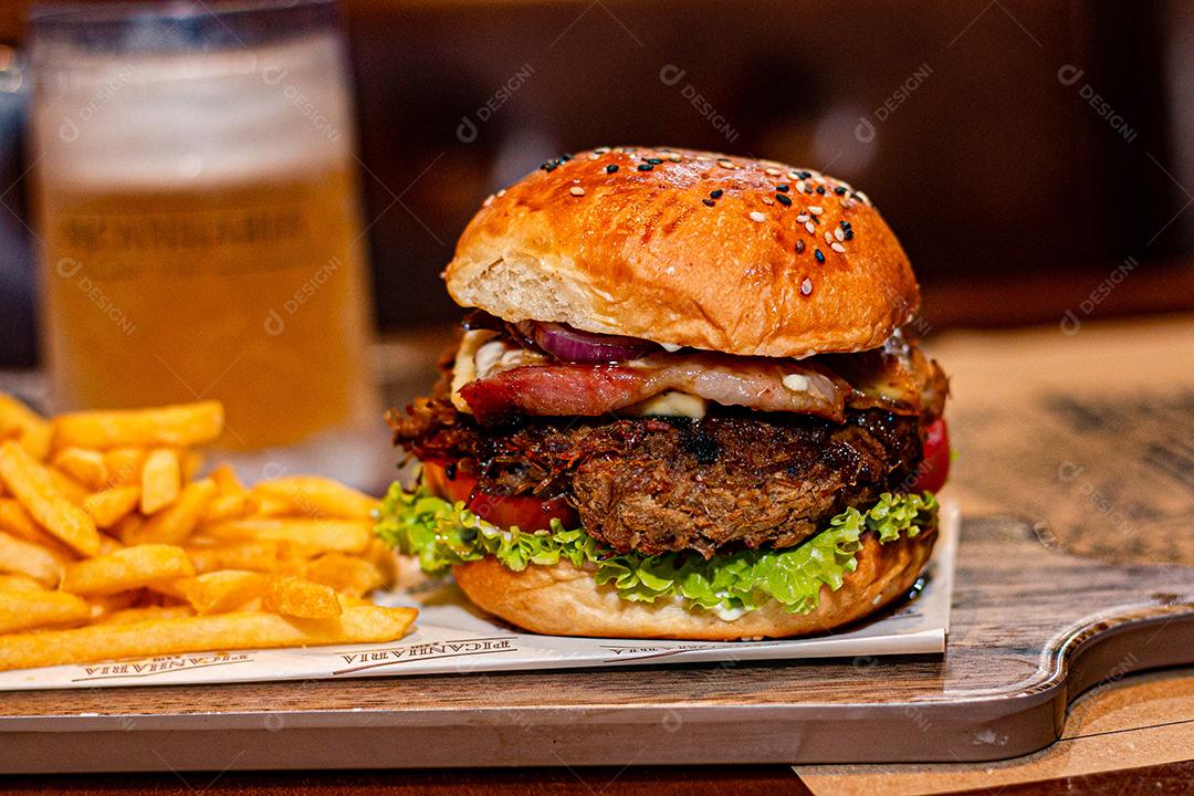 Hambúrguer com batata frita servidos em tabua de madeira