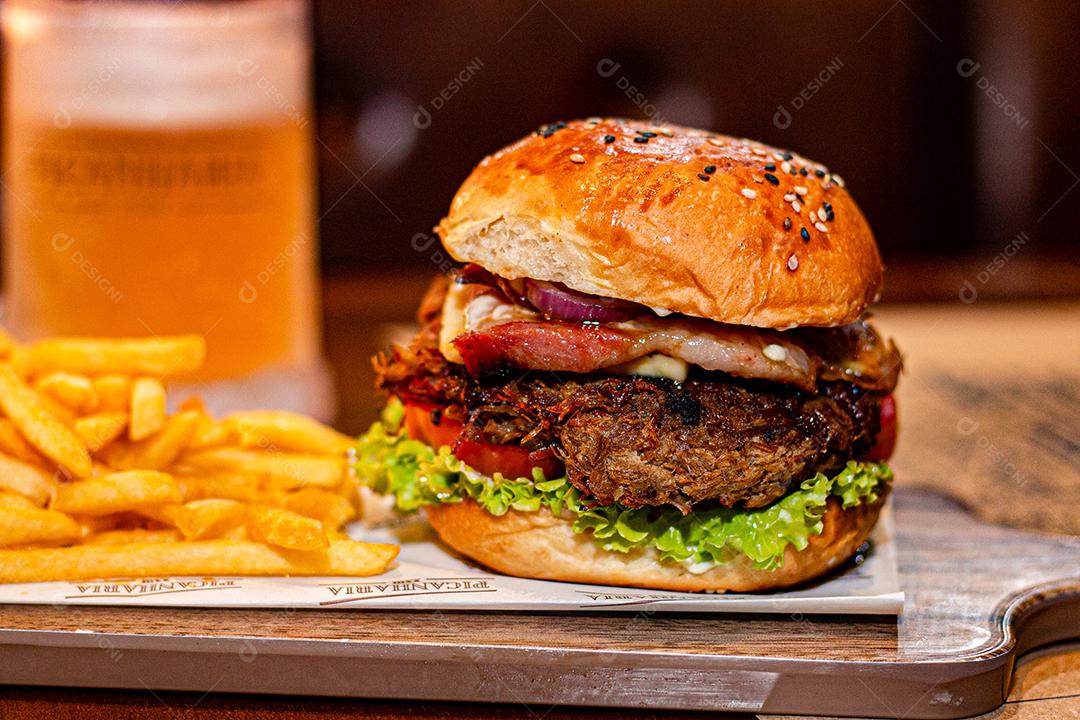 Hambúrguer com batata frita servidos em tabua de madeira