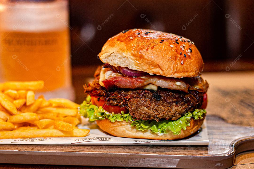 Hambúrguer com batata frita servidos em tabua de madeira