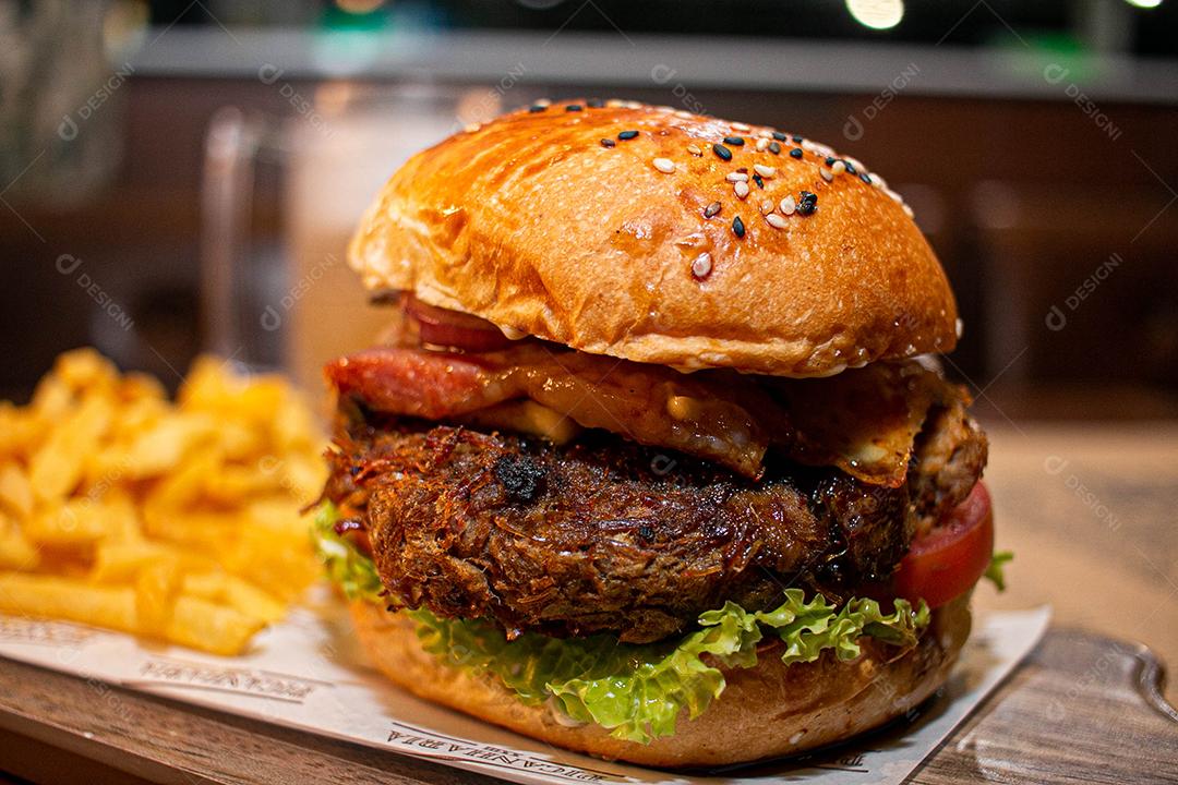 Hambúrguer com batata frita servidos em tabua de madeira