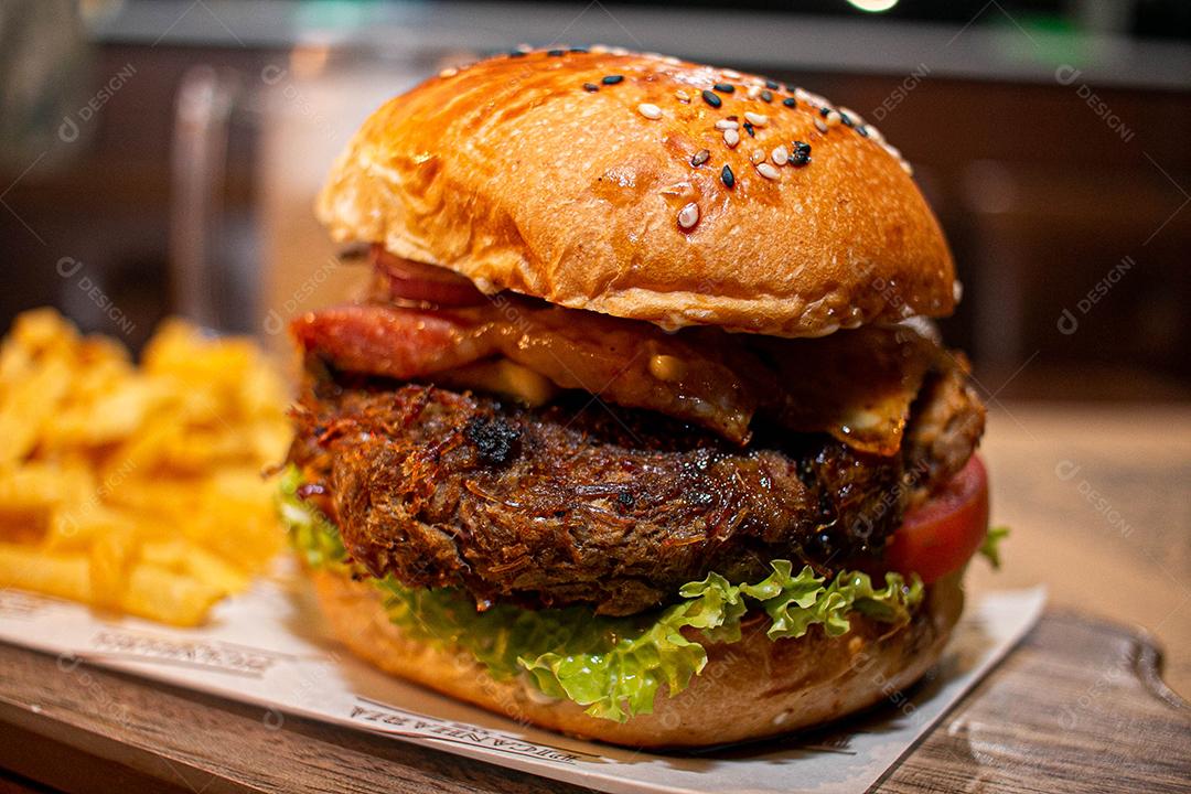 Hambúrguer com batata frita servidos em tabua de madeira