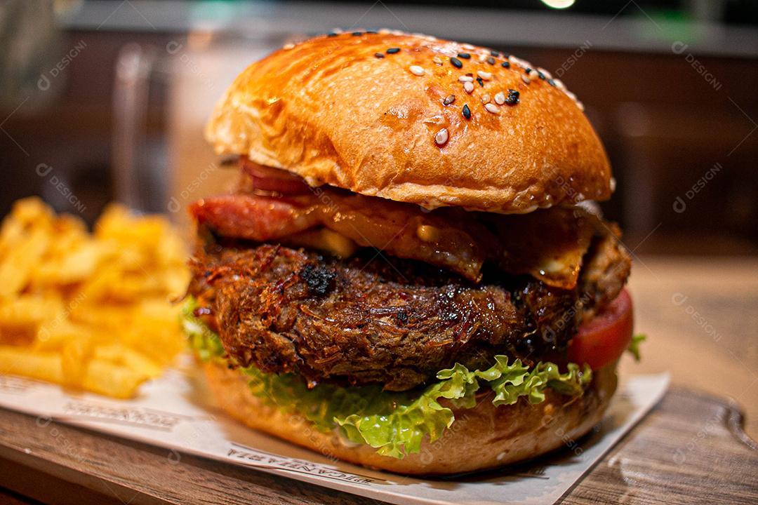 Hambúrguer com batata frita servidos em tabua de madeira