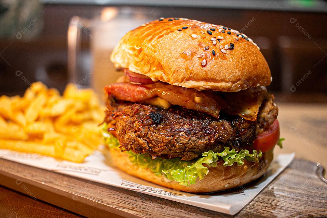 Hambúrguer com batata frita servidos em tabua de madeira