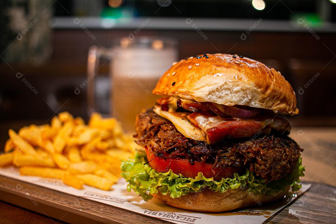 Hambúrguer com batata frita servidos em tabua de madeira