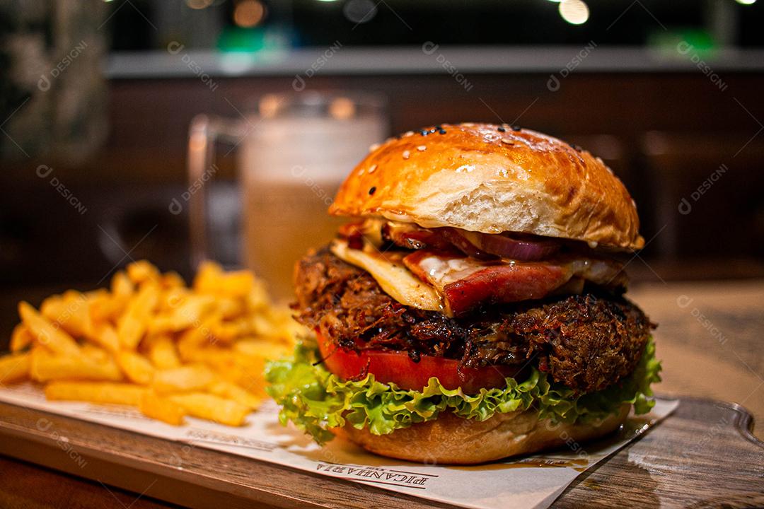 Hambúrguer com batata frita servidos em tabua de madeira