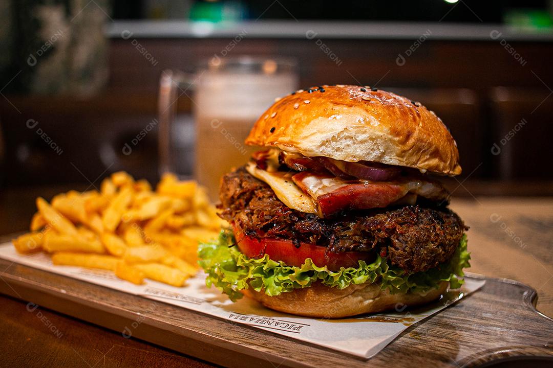 Hambúrguer com batata frita servidos em tabua de madeira