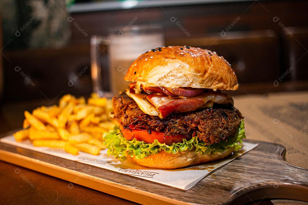 Hambúrguer com batata frita servidos em tabua de madeira