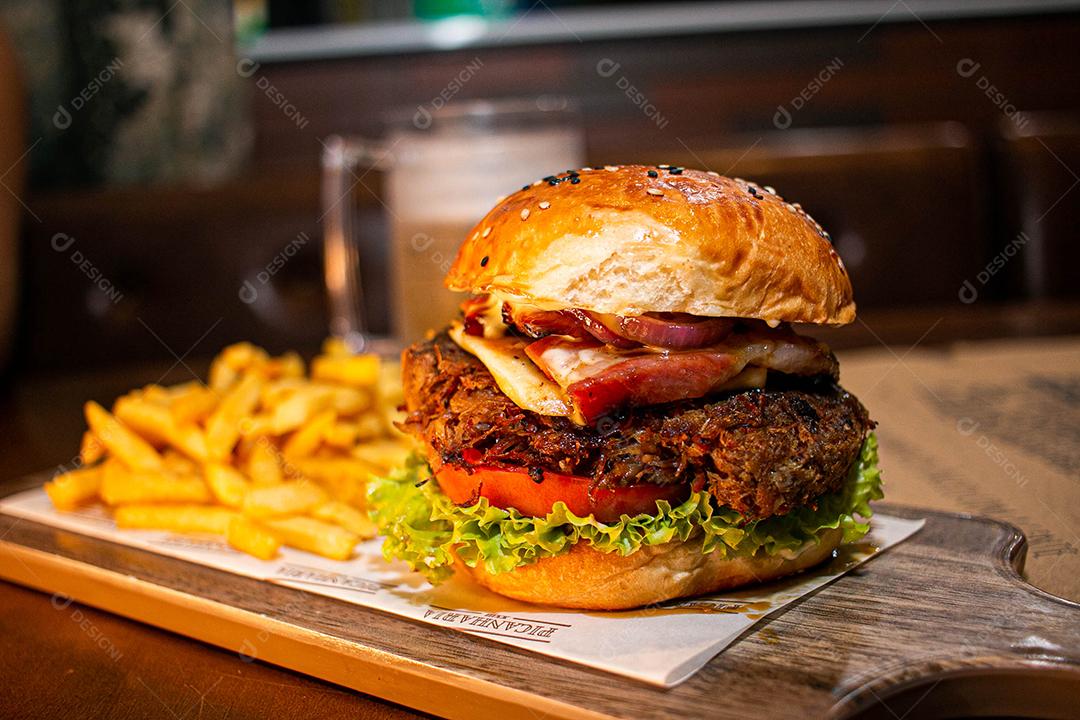 Hambúrguer com batata frita servidos em tabua de madeira