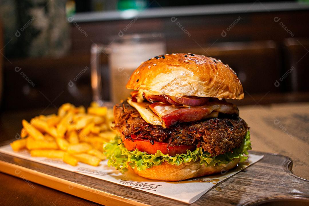Hambúrguer com batata frita servidos em tabua de madeira