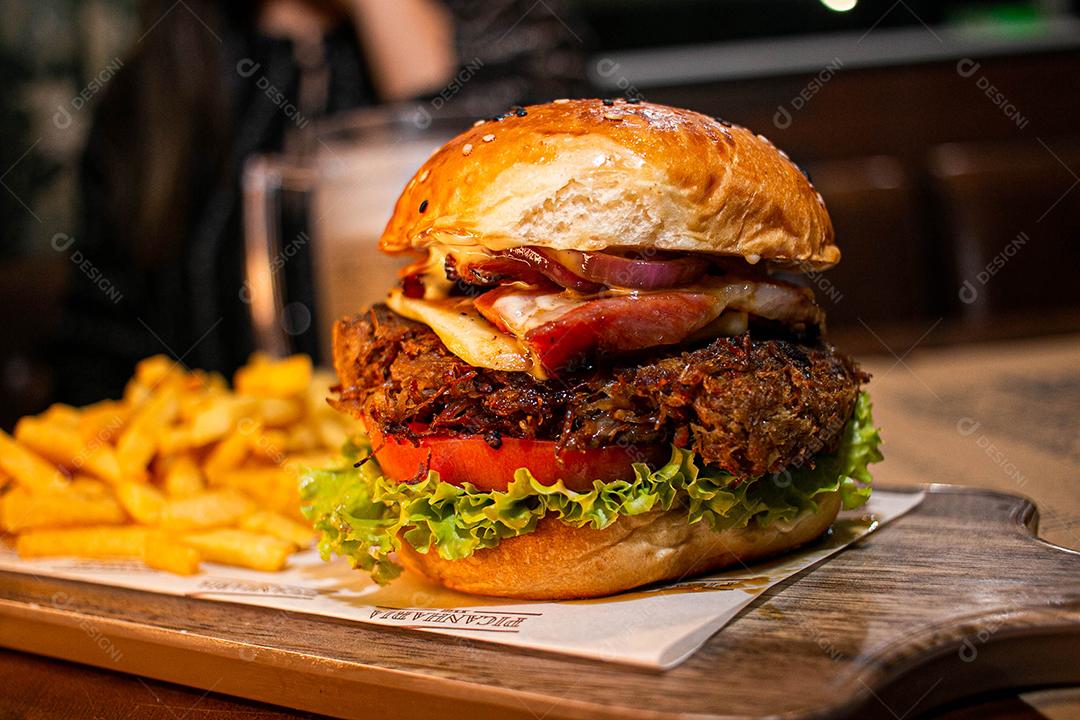 Hambúrguer com batata frita servidos em tabua de madeira