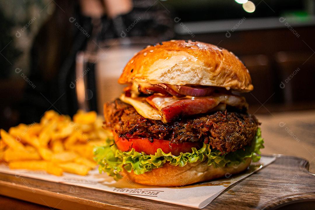 Hambúrguer com batata frita servidos em tabua de madeira