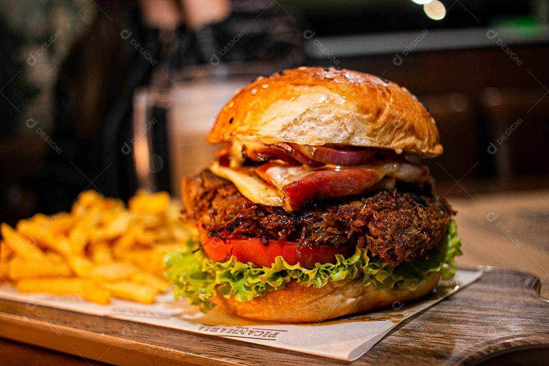 Hambúrguer com batata frita servidos em tabua de madeira