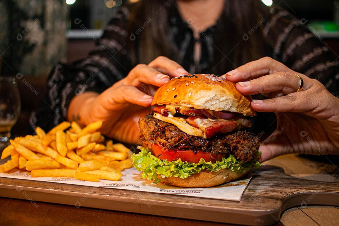 Hambúrguer com batata frita servidos em tabua de madeira