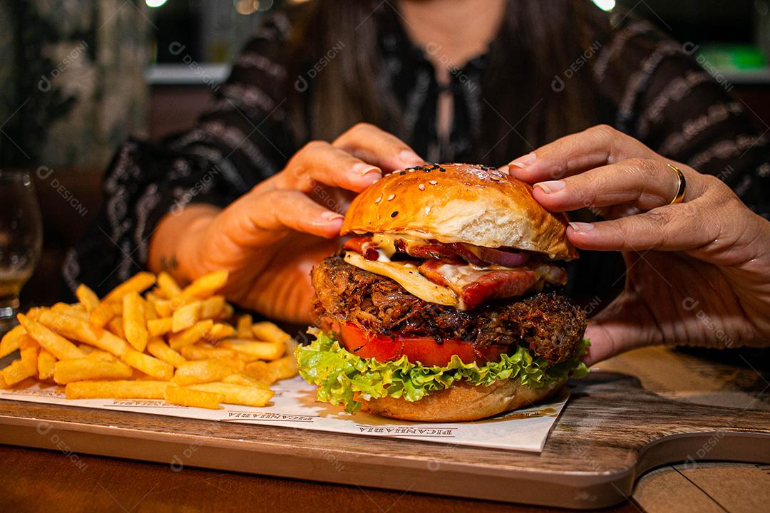 Hambúrguer com batata frita servidos em tabua de madeira