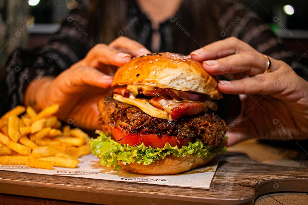 Hambúrguer com batata frita servidos em tabua de madeira