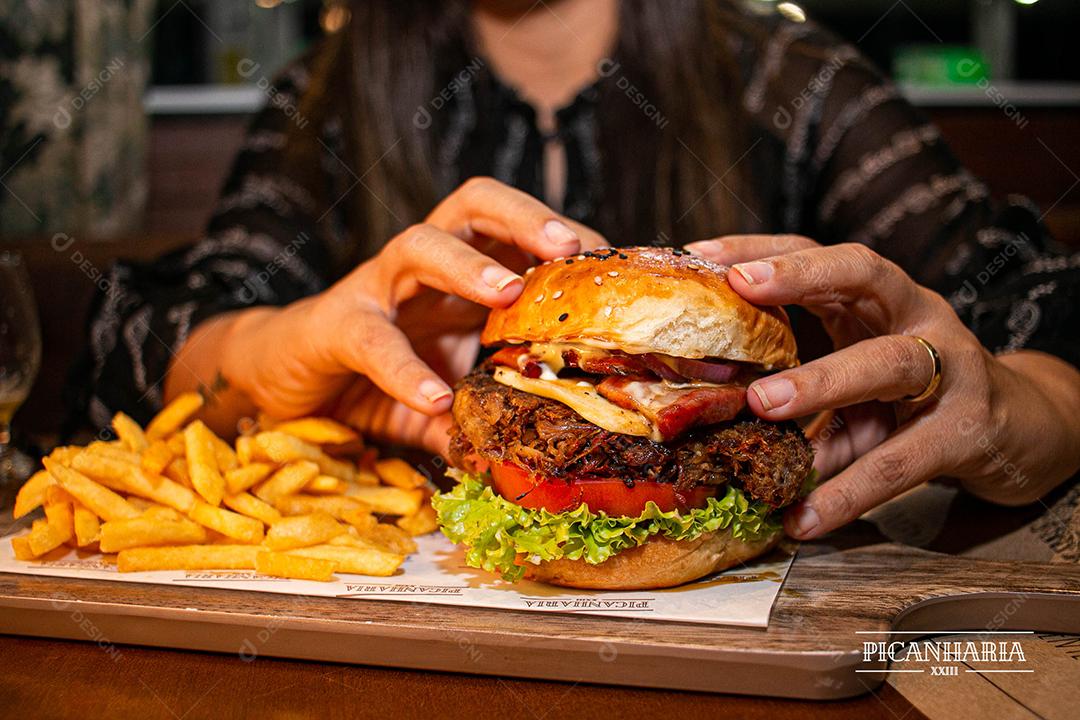 Hambúrguer com batata frita servidos em tabua de madeira
