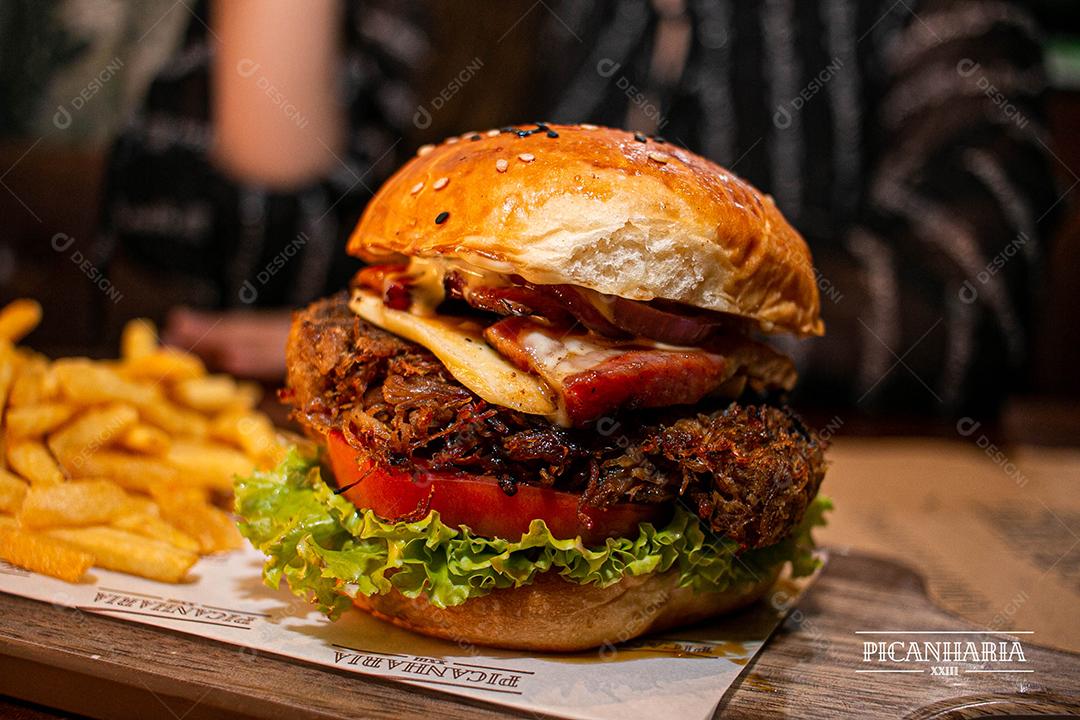 Hambúrguer com batata frita servidos em tabua de madeira