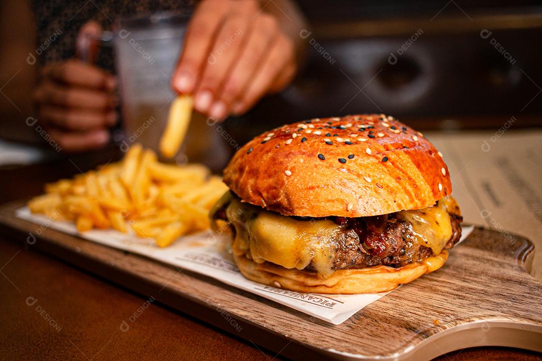 Hambúrguer com batata frita servidos em tabua de madeira