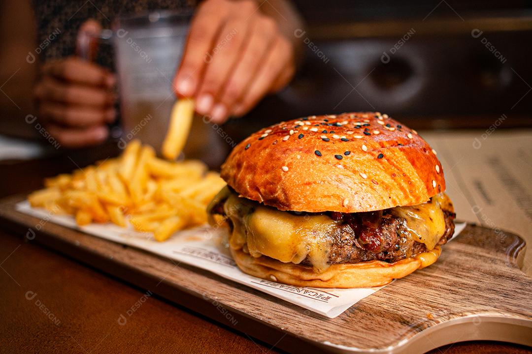Hambúrguer com batata frita servidos em tabua de madeira