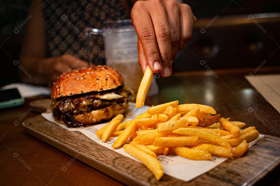 Hambúrguer com batata frita servidos em tabua de madeira