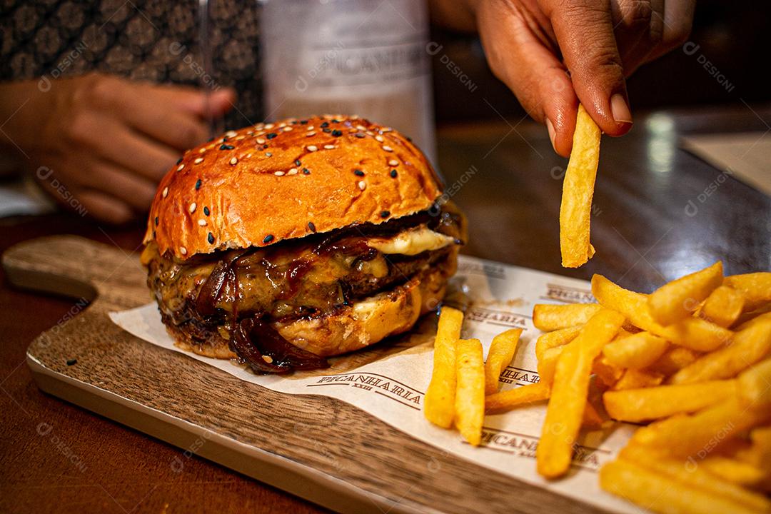 Hambúrguer com batata frita servidos em tabua de madeira