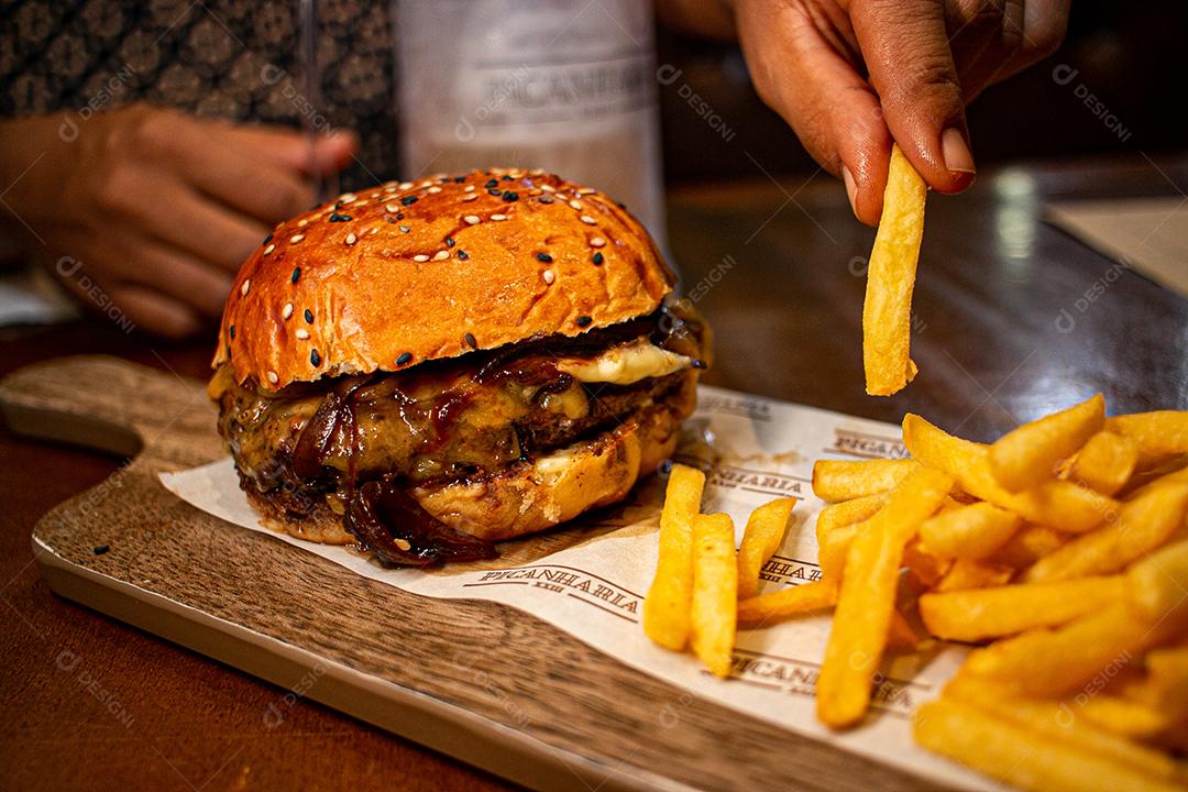 Hambúrguer com batata frita servidos em tabua de madeira