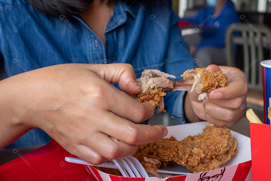 comendo frango frito na mão em restaurante de fast food, junk food