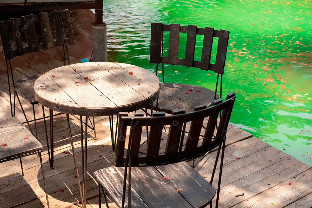 Mesas e cadeiras são colocadas ao lado da piscina no jardim de jantar. Em meio a um ambiente agradável e sombrio