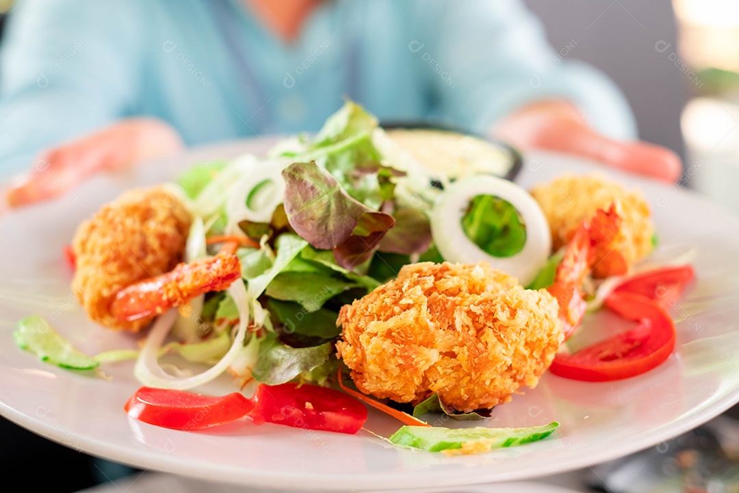 Salada fresca de verão com camarões, tomate cereja e pepinos em uma tigela sobre a mesa de fogo. O conceito de alimentação saudável.