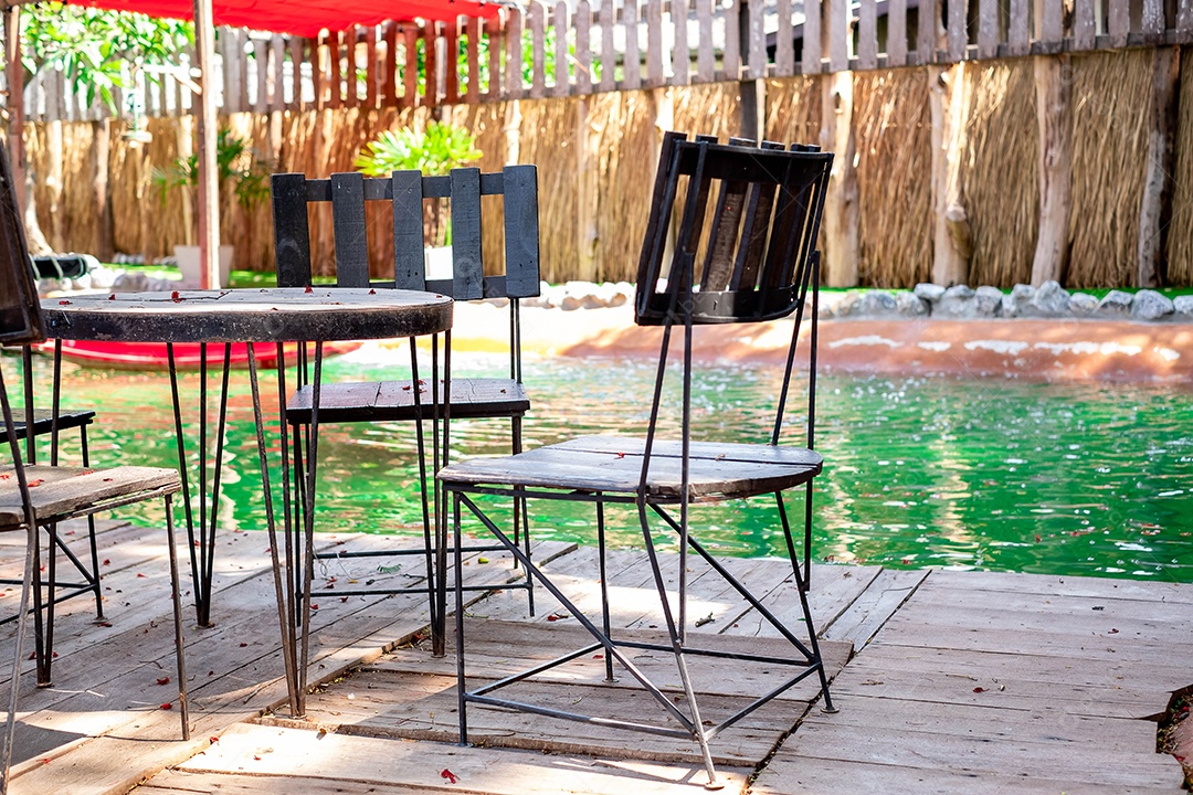 Mesas e cadeiras são colocadas ao lado da piscina no jardim de jantar. Em meio a um ambiente agradável e sombrio