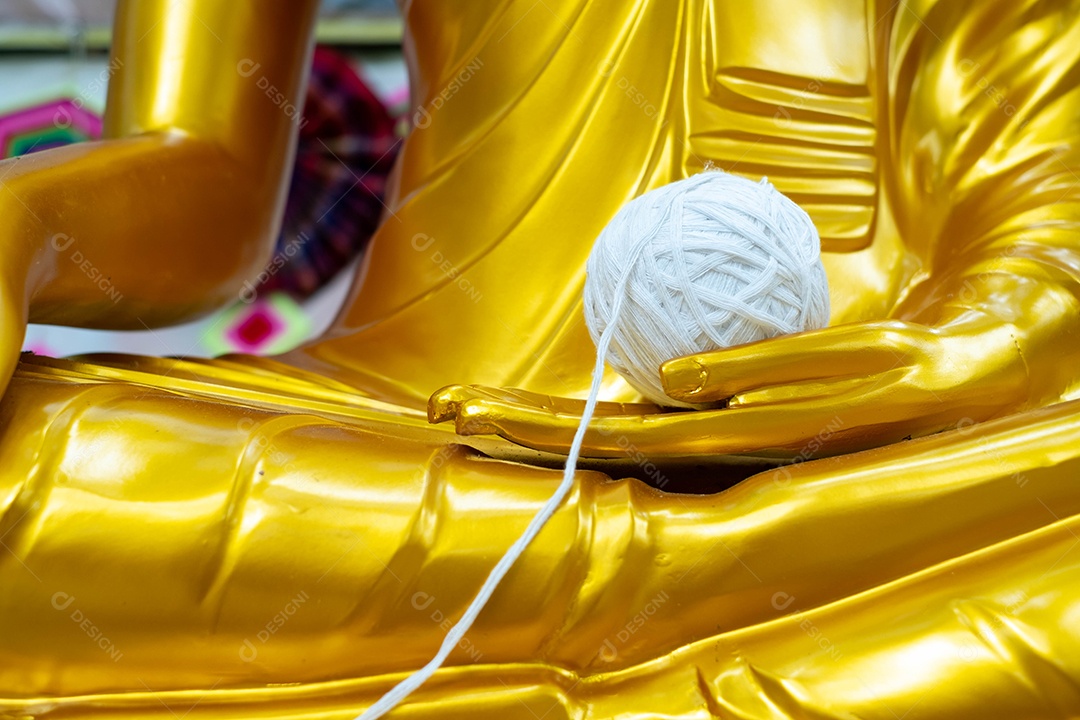 Estatua de Buda de ouro com uma bolinha de barbante na mão