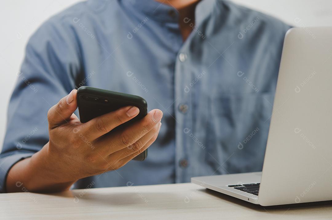 Homem usando telefone inteligente móvel e laptop de computador pesquisando na internet