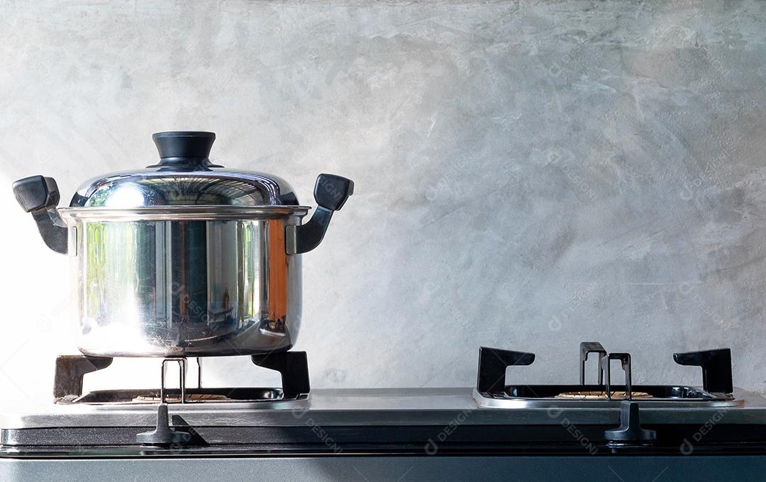 panela de ferro em um fogão a gás preto em uma cozinha, desfoque de cimento cinza para fundo, macro