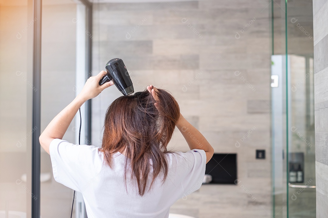 jovem usando secador de cabelo em casa ou hotel. Penteados e conceitos de estilo de vida