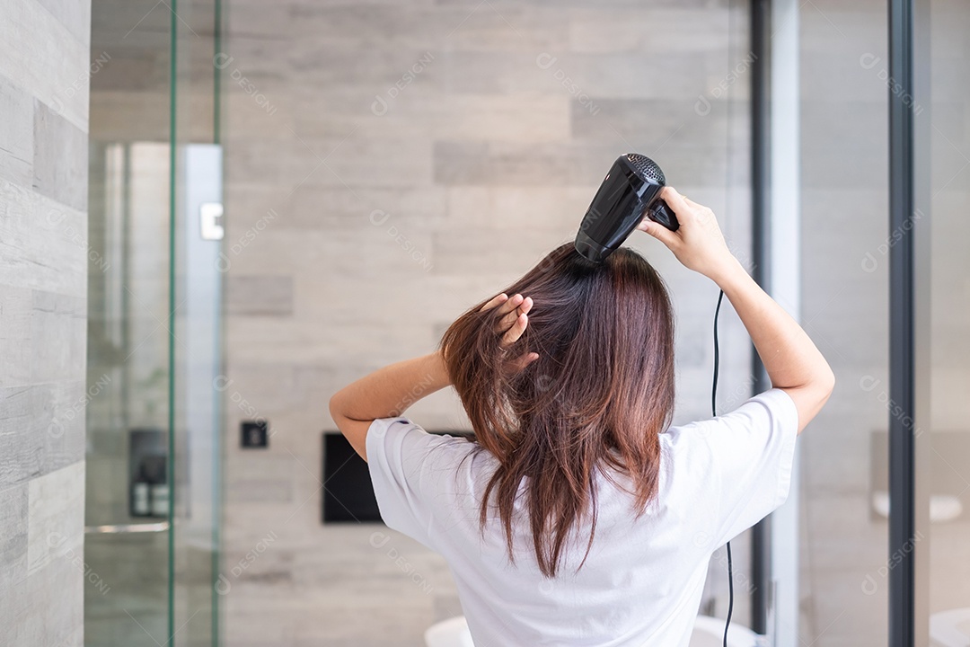 jovem usando secador de cabelo em casa ou hotel. Penteados e conceitos de estilo de vida