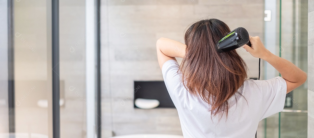 jovem usando secador de cabelo em casa ou hotel. Penteados e conceitos de estilo de vida