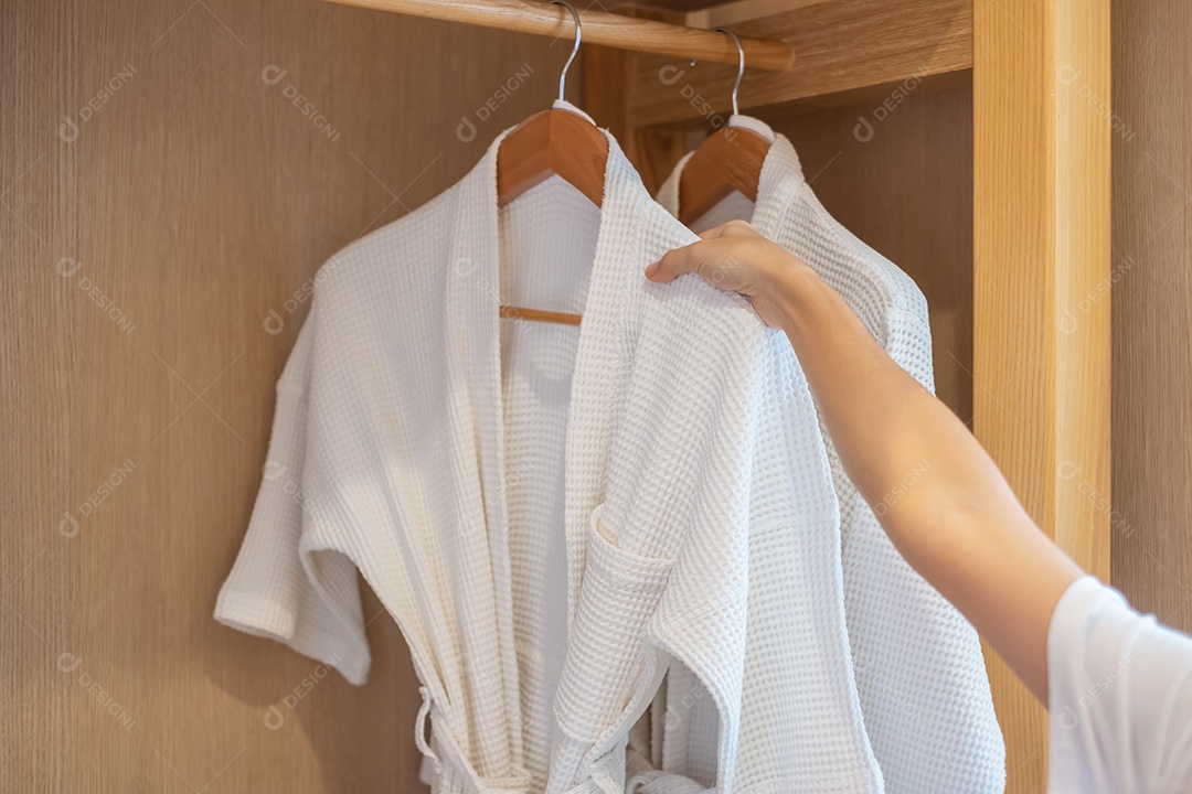 Roupão de banho limpo branco pendurado no guarda-roupa de madeira no hotel de luxo ou em casa. Relaxe e viaje o conceito