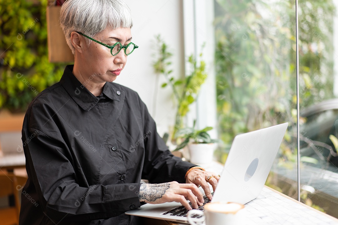 Mulher sênior asiática ativa assistindo e trabalhando no laptop no